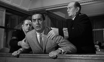 Movie still from “Witness for the Prosecution” (1957), directed by Billy Wilder – A man in a suit and tie sitting in front of two other men; Medium shot, Low angle