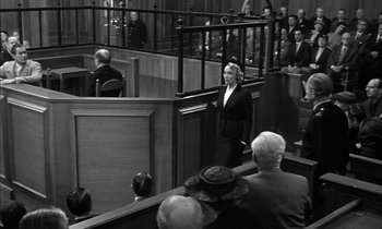 Movie still from “Witness for the Prosecution” (1957), directed by Billy Wilder – A woman standing in front of a crowd in a courtroom; Wide shot, Low angle
