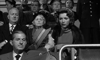 Movie still from “Witness for the Prosecution” (1957), directed by Billy Wilder – A group of people sitting in a stadium; Medium shot, Over the shoulder angle