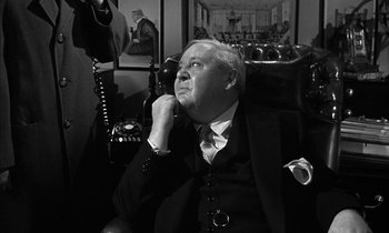 Movie still from “Witness for the Prosecution” (1957), directed by Billy Wilder – An older man sitting in a chair looking up at the sky; Close Up shot, Over the shoulder angle