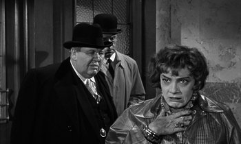 Movie still from “Witness for the Prosecution” (1957), directed by Billy Wilder – A man and a woman standing next to each other in front of a building; Medium shot, Over the shoulder angle