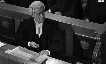 Movie still from “Witness for the Prosecution” (1957), directed by Billy Wilder – An old photo of a judge sitting in a court room; Medium shot, High angle