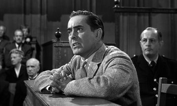 Movie still from “Witness for the Prosecution” (1957), directed by Billy Wilder – An old photo of a man in a suit sitting in a courtroom; Medium shot, Low angle