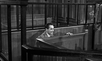 Movie still from “Witness for the Prosecution” (1957), directed by Billy Wilder – A black and white photo of a man sitting in a courtroom; Medium shot, High angle