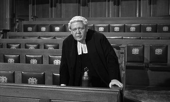 Movie still from “Witness for the Prosecution” (1957), directed by Billy Wilder – An old man in a courtroom with a judge's wig on; Medium shot, High angle