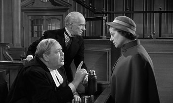 Movie still from “Witness for the Prosecution” (1957), directed by Billy Wilder – A man and a woman talking to an older man; Medium shot, Over the shoulder angle