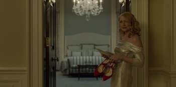 Movie still from “House of Cards” (2013), created by Beau Willimon – A woman holding a pair of red high heeled shoes; Medium shot, Low angle