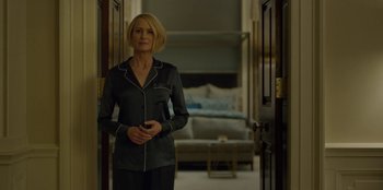 Movie still from “House of Cards” (2013), created by Beau Willimon – A woman standing in a living room wearing pajamas; Medium shot, Low angle