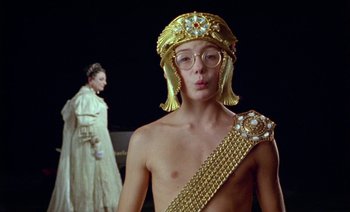 Movie still from “Wittgenstein” (1993), directed by Derek Jarman – A man wearing a gold crown and a gold robe; Close Up shot, Over the shoulder angle