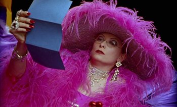 Movie still from “Wittgenstein” (1993), directed by Derek Jarman – A woman wearing a pink hat and a pink dress; Close Up shot, Over the shoulder angle