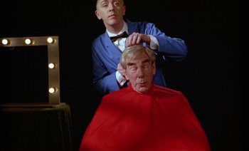 Movie still from “Wittgenstein” (1993), directed by Derek Jarman – A man sitting in front of another man in a chair; Medium shot, Low angle