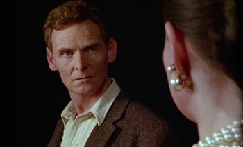 Movie still from “Wittgenstein” (1993), directed by Derek Jarman – A man looking into a mirror while standing next to a woman; Close Up shot, Over the shoulder angle