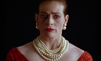 Movie still from “Wittgenstein” (1993), directed by Derek Jarman – A person wearing a necklace with pearls; Close Up shot, Low angle