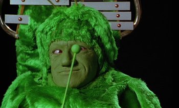 Movie still from “Wittgenstein” (1993), directed by Derek Jarman – A man in a green costume with a ball in his mouth; Extreme Close Up shot, Low angle