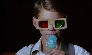 Movie still from “Wittgenstein” (1993), directed by Derek Jarman – A young boy wearing 3 - d glasses and holding a drink; Close Up shot, High angle