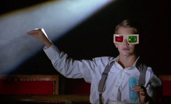 Movie still from “Wittgenstein” (1993), directed by Derek Jarman – A person wearing 3 d glasses holding a remote control; Medium shot, Low angle