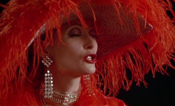 Movie still from “Wittgenstein” (1993), directed by Derek Jarman – A woman in a red dress and a red hat; Close Up shot, Low angle