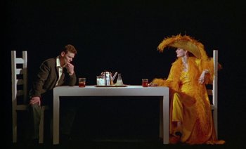 Movie still from “Wittgenstein” (1993), directed by Derek Jarman – A man and a woman sitting at a dinner table; Wide shot, Overhead angle