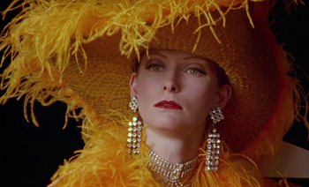 Movie still from “Wittgenstein” (1993), directed by Derek Jarman – A woman wearing a large hat with feathers around her neck; Close Up shot, Low angle