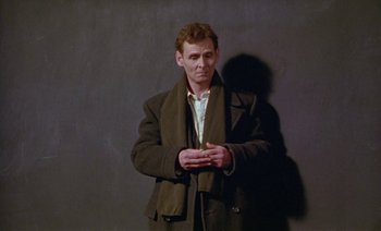 Movie still from “Wittgenstein” (1993), directed by Derek Jarman – A man wearing a jacket and a scarf; Medium shot, Low angle
