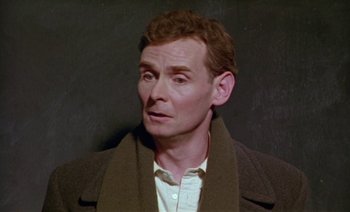 Movie still from “Wittgenstein” (1993), directed by Derek Jarman – A person wearing a jacket; Close Up shot, High angle