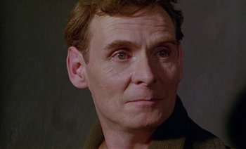 Movie still from “Wittgenstein” (1993), directed by Derek Jarman – A person wearing a brown jacket; Close Up shot, Low angle