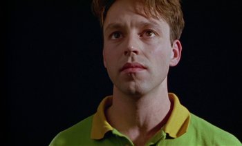 Movie still from “Wittgenstein” (1993), directed by Derek Jarman – A young man in a yellow and green polo shirt; Close Up shot, Low angle