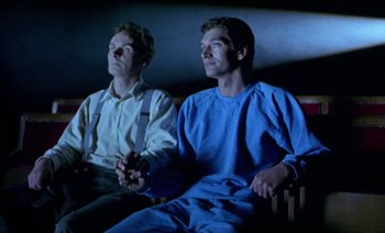 Movie still from “Wittgenstein” (1993), directed by Derek Jarman – A couple of men sitting next to each other on a bench; Medium shot, Low angle