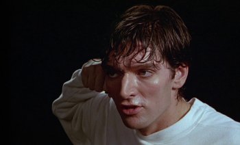 Movie still from “Wittgenstein” (1993), directed by Derek Jarman – A person wearing a white shirt; Close Up shot, Low angle