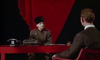 Movie still from “Wittgenstein” (1993), directed by Derek Jarman – A person sitting at a table with a typewriter; Medium shot, Over the shoulder angle