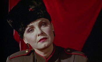 Movie still from “Wittgenstein” (1993), directed by Derek Jarman – A woman in a military uniform wearing a black hat; Close Up shot, Low angle
