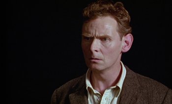 Movie still from “Wittgenstein” (1993), directed by Derek Jarman – A person wearing a jacket; Close Up shot, Low angle