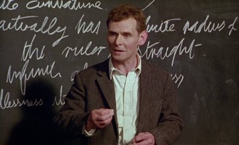 Movie still from “Wittgenstein” (1993), directed by Derek Jarman – A man standing in front of a chalkboard; Medium shot, Low angle