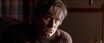 Movie still from “Wonder Boys” (2000), directed by Curtis Hanson – An older man wearing a purple sweater looking at the camera; Close Up shot, Low angle