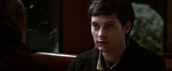 Movie still from “Wonder Boys” (2000), directed by Curtis Hanson – A man sitting in front of a wooden table; Close Up shot, High angle
