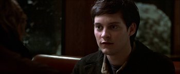 Movie still from “Wonder Boys” (2000), directed by Curtis Hanson – A man sitting in front of a wooden table; Close Up shot, High angle