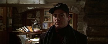 Movie still from “Wonder Boys” (2000), directed by Curtis Hanson – A man wearing a yankees hat in a room; Close Up shot, Over the shoulder angle