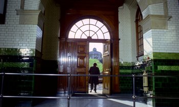 Movie still from “Wonderwall” (1968), directed by Joe Massot – A man standing in front of a door way; Extreme Wide shot, Low angle