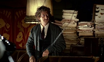 A man in a suit and tie standing in front of a pile of papers