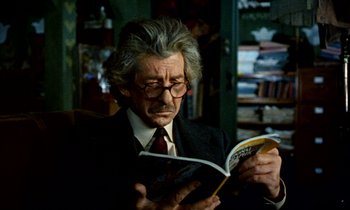 Movie still from “Wonderwall” (1968), directed by Joe Massot – An older man in a suit and tie reading a book; Close Up shot, Over the shoulder angle