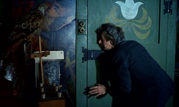 Movie still from “Wonderwall” (1968), directed by Joe Massot – A man standing in front of an open green door; Medium shot, Over the shoulder angle