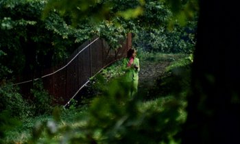 A woman in a green suit walking in the woods