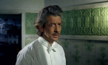 Movie still from “Wonderwall” (1968), directed by Joe Massot – A person wearing a shirt and tie; Close Up shot, Over the shoulder angle