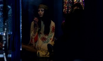 Movie still from “Wonderwall” (1968), directed by Joe Massot – A woman sitting on the ground smoking a cigarette in front of a mirror; Medium shot, Over the shoulder angle