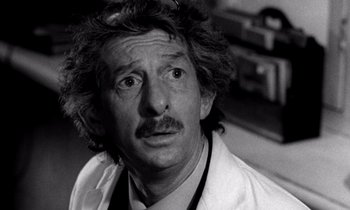 Movie still from “Wonderwall” (1968), directed by Joe Massot – Black and white photograph of a man in a lab coat; Close Up shot, Over the shoulder angle