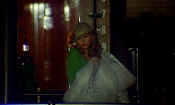 Movie still from “Wonderwall” (1968), directed by Joe Massot – A woman in a green sweater holding a white bag; Medium shot, Overhead angle