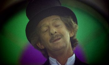 Movie still from “Wonderwall” (1968), directed by Joe Massot – A person wearing a top hat; Close Up shot, Low angle