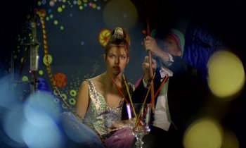 Movie still from “Wonderwall” (1968), directed by Joe Massot – A woman sitting at a table with a glass of wine; Medium shot, Low angle