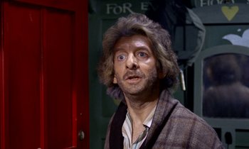 Movie still from “Wonderwall” (1968), directed by Joe Massot – A wax figure of an old man in front of a red door; Close Up shot, Over the shoulder angle