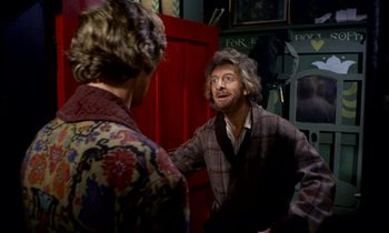 Movie still from “Wonderwall” (1968), directed by Joe Massot – Two men are talking in a room with red walls; Medium shot, Over the shoulder angle